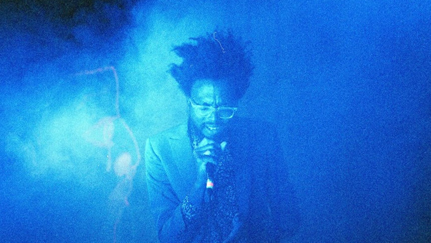 An image of Tolliver singing in blue light