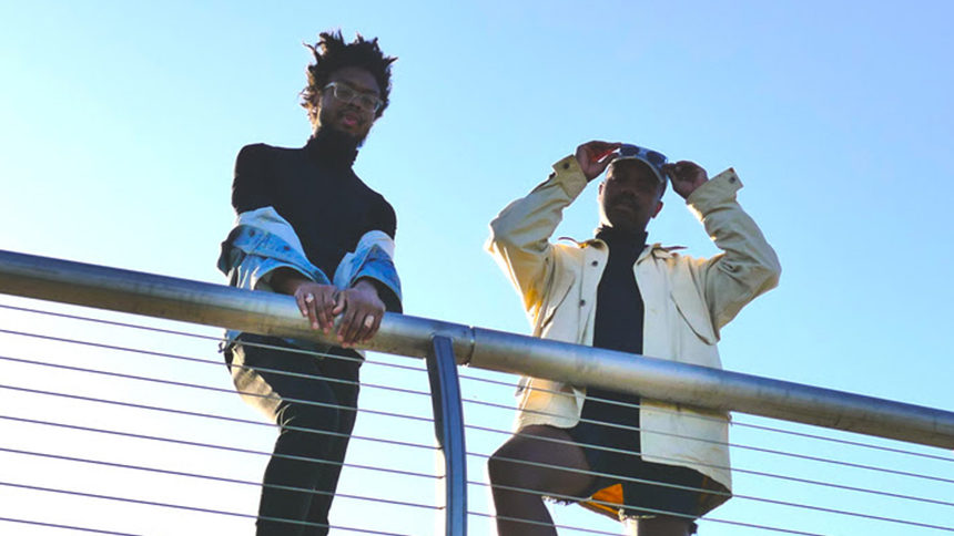 An image of Tolliver and Eddington leaning near a railing