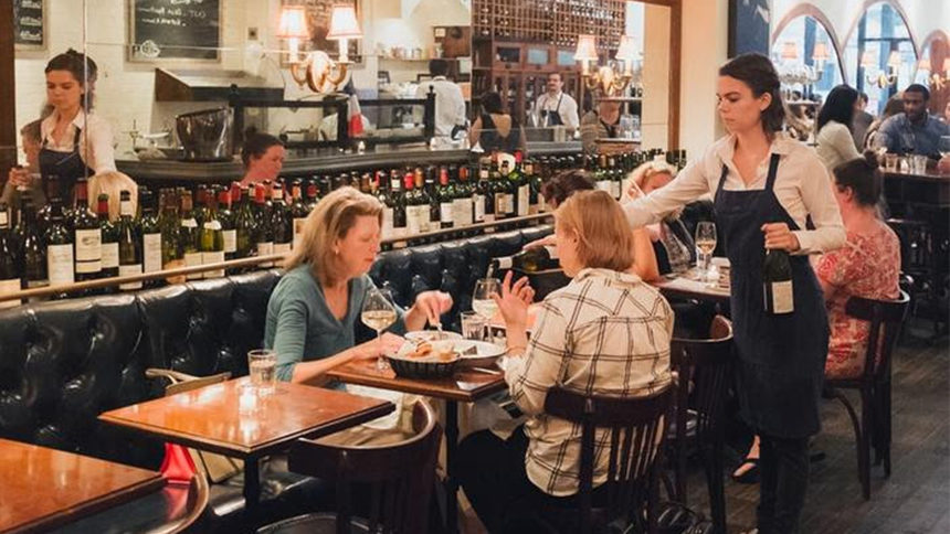 A waitress working at Vin Sur Vingt in new York City serves wine to two dining patrons
